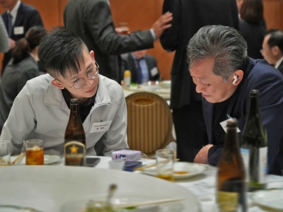 交流会の懇親会で、欣泉光印の開発担当者が日本企業の代表と技術的な内容について話し合い、テーブル上の資料を確認している様子。